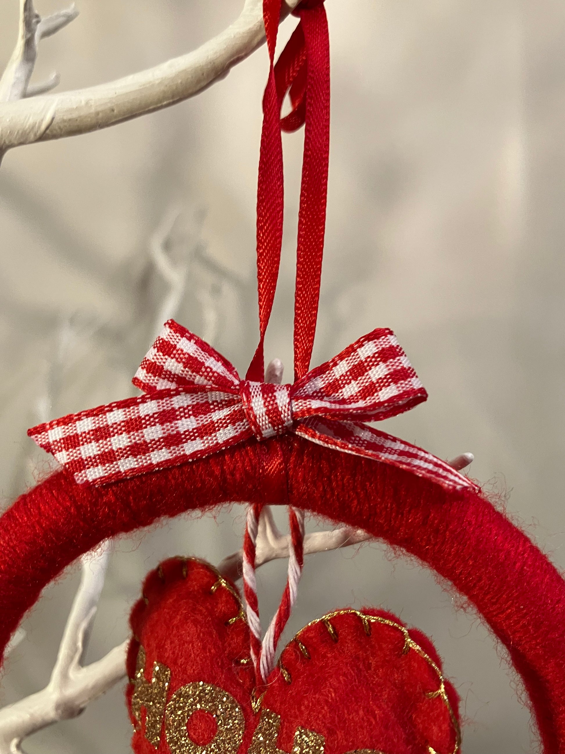Top of the red wreath showing a red and white checkered bow and hanging ribbon.