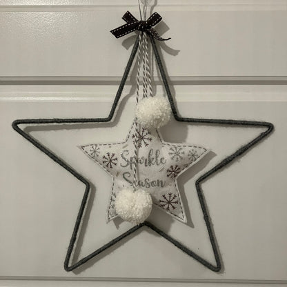 Gray wire star with a fabric star inside that says "Sparkle Season" and two white pom-poms.