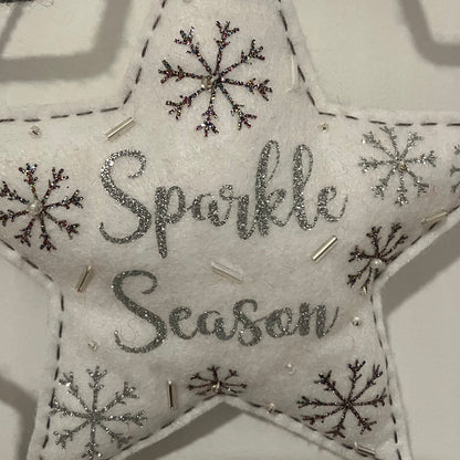 White felt star ornament with "Sparkle Season" in glitter, surrounded by snowflakes and beads.
