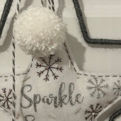 White felt star ornament with "Sparkle" in glitter, snowflakes, beads, and a pom-pom.