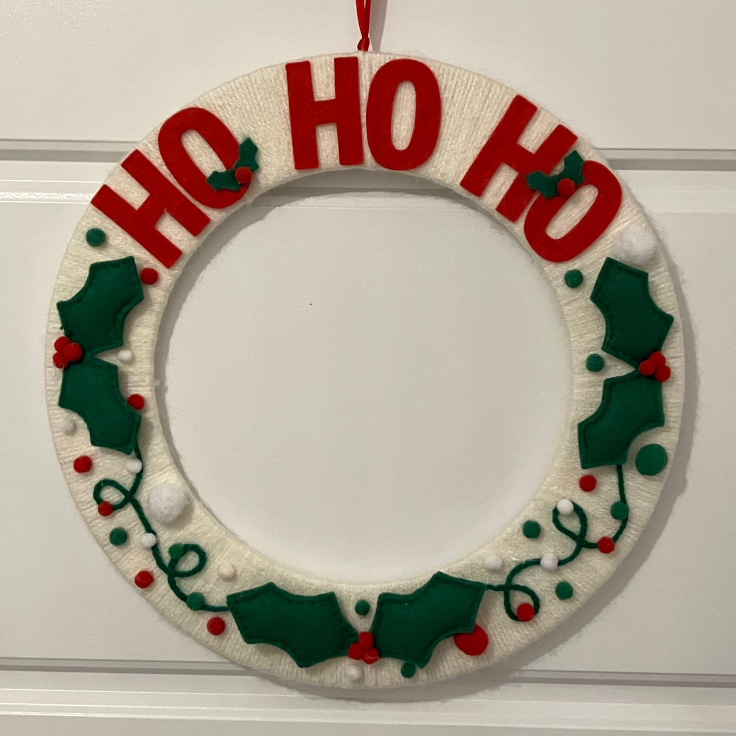 Handmade Christmas wreath with "HO HO HO" in red letters and felt holly leaves.