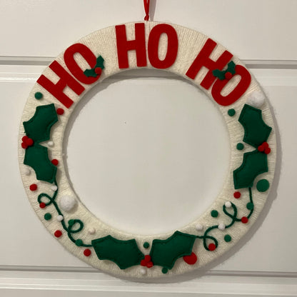 Handmade Christmas wreath with "HO HO HO" in red letters and felt holly leaves.