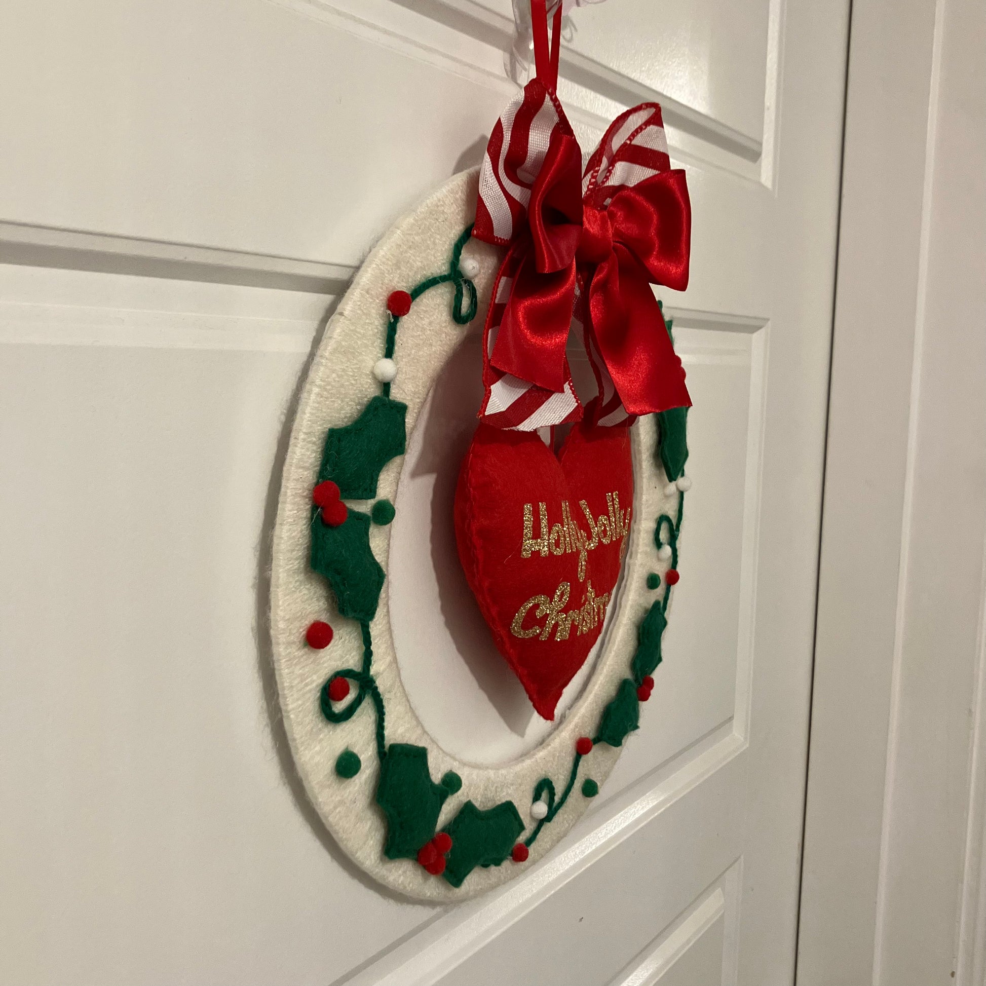 White felt wreath with green holly, red berries, and a red heart with "Holly Jolly Christmas" embroidered.