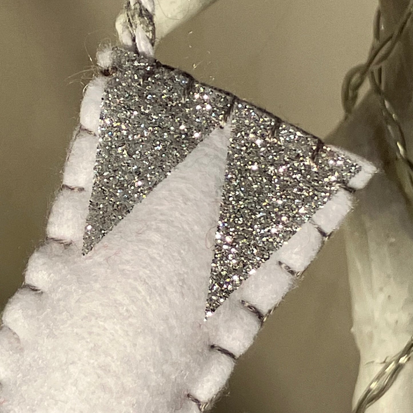 White felt Christmas stocking with silver glitter triangles and black stitching.