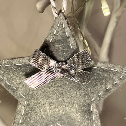 Handmade gray felt star ornament with white stitching and a silver bow.