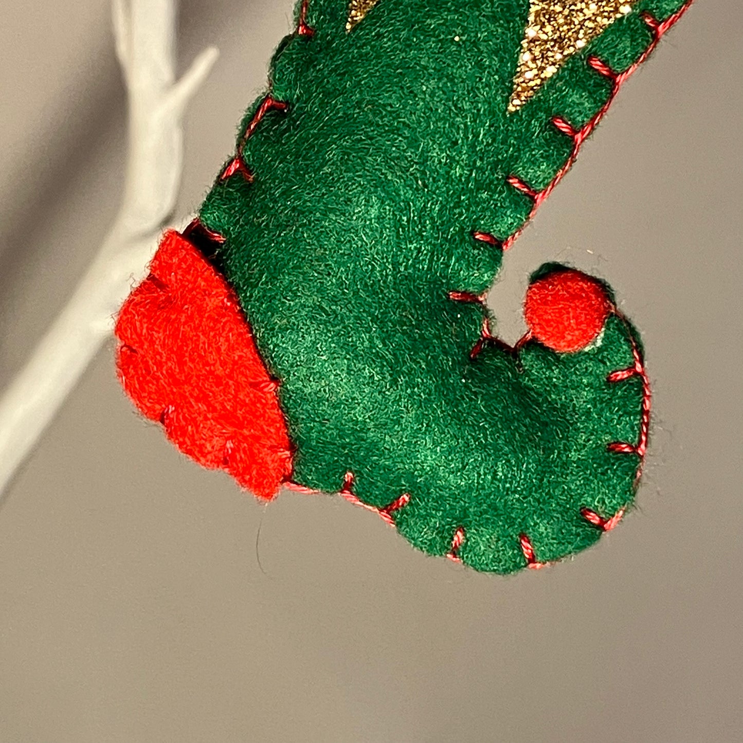 Green felt elf shoe ornament with red trim and a gold glitter cuff.