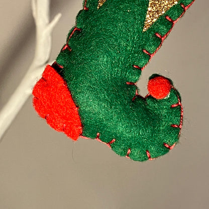 Green felt elf shoe ornament with red trim and a gold glitter cuff.
