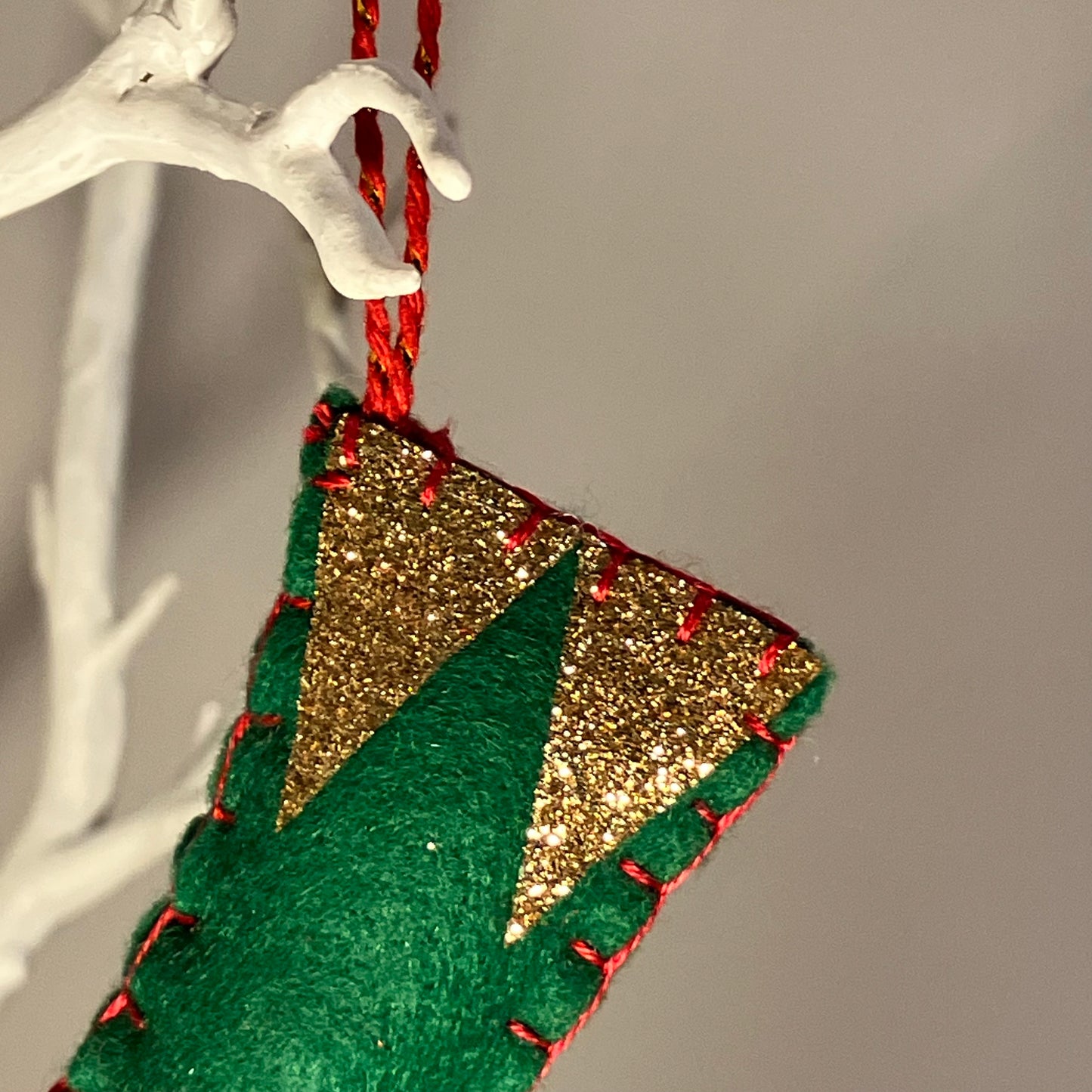 Green and gold glitter felt Christmas stocking ornament with red stitching.