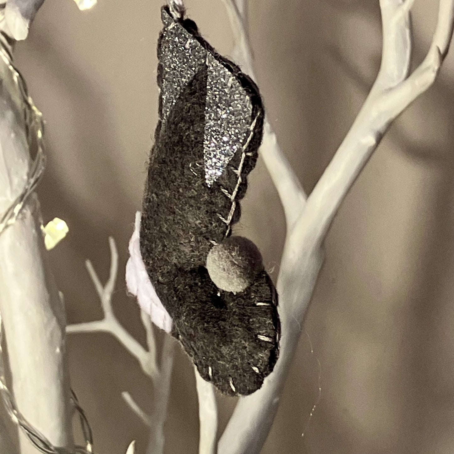 Handmade dark gray felt bat ornament with glitter wings and a small pom-pom nose.