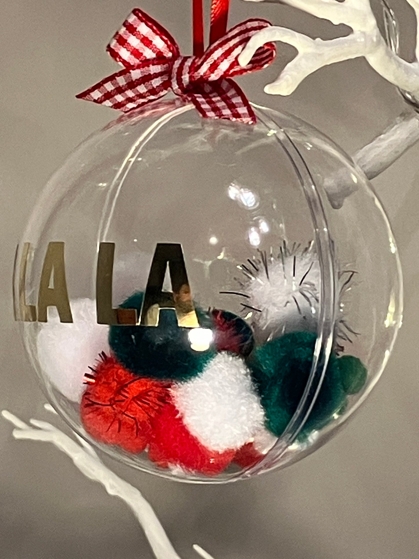 Clear ornament with red and white gingham bow, filled with colorful pom-poms and the word "LALA".