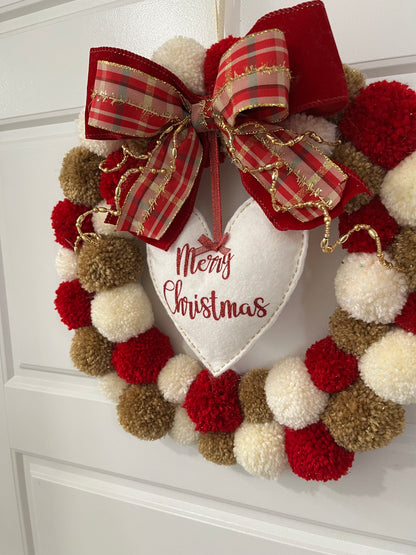 A whimsical Christmas wreath made of red, white, and brown pom-poms with a festive bow.