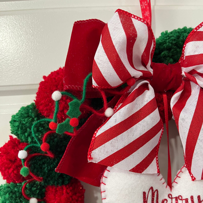Side view of a Christmas wreath with a 'Merry Christmas' heart, bows, and holly accents.
