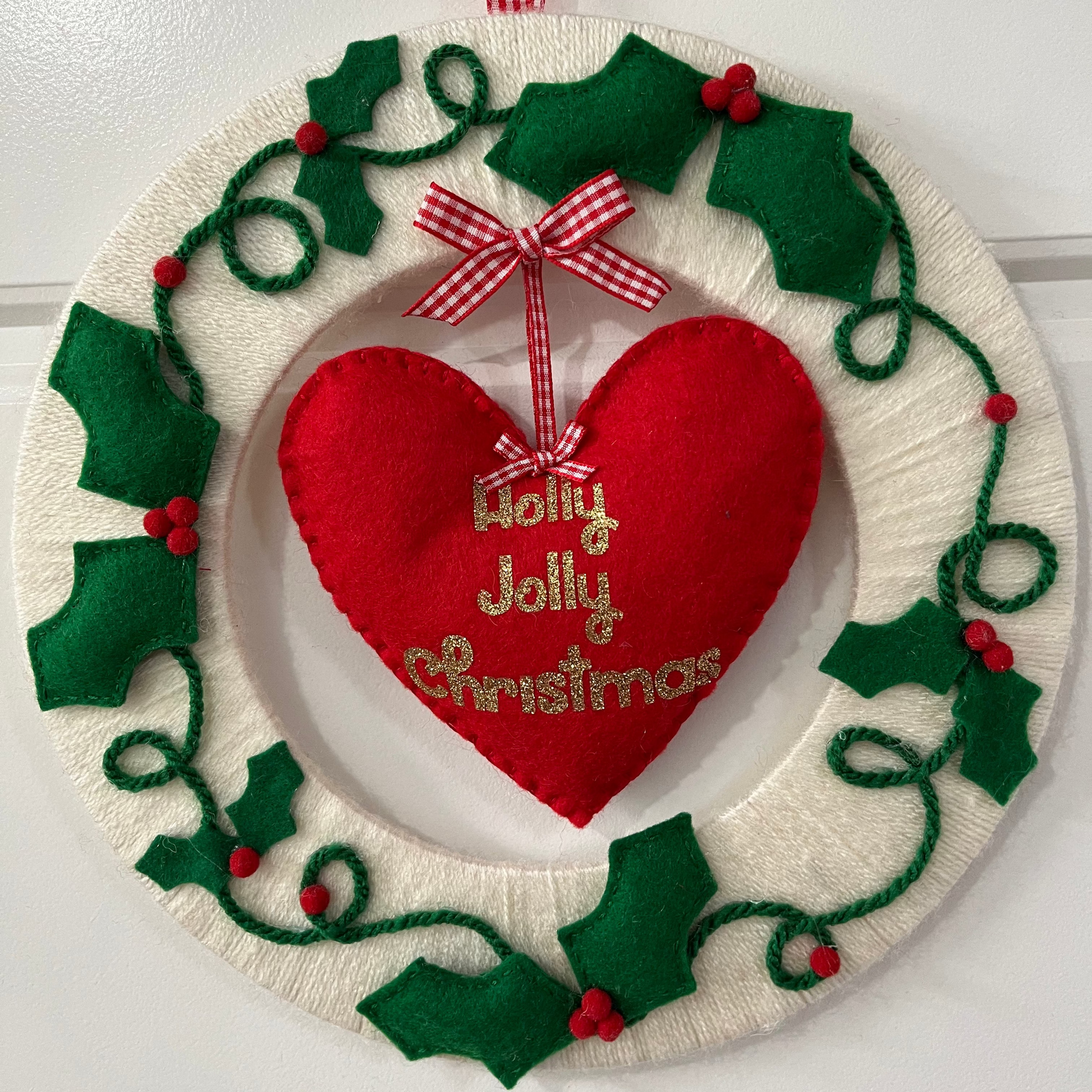 Festive Holly Jolly Christmas wreath with a red heart and green holly leaves.