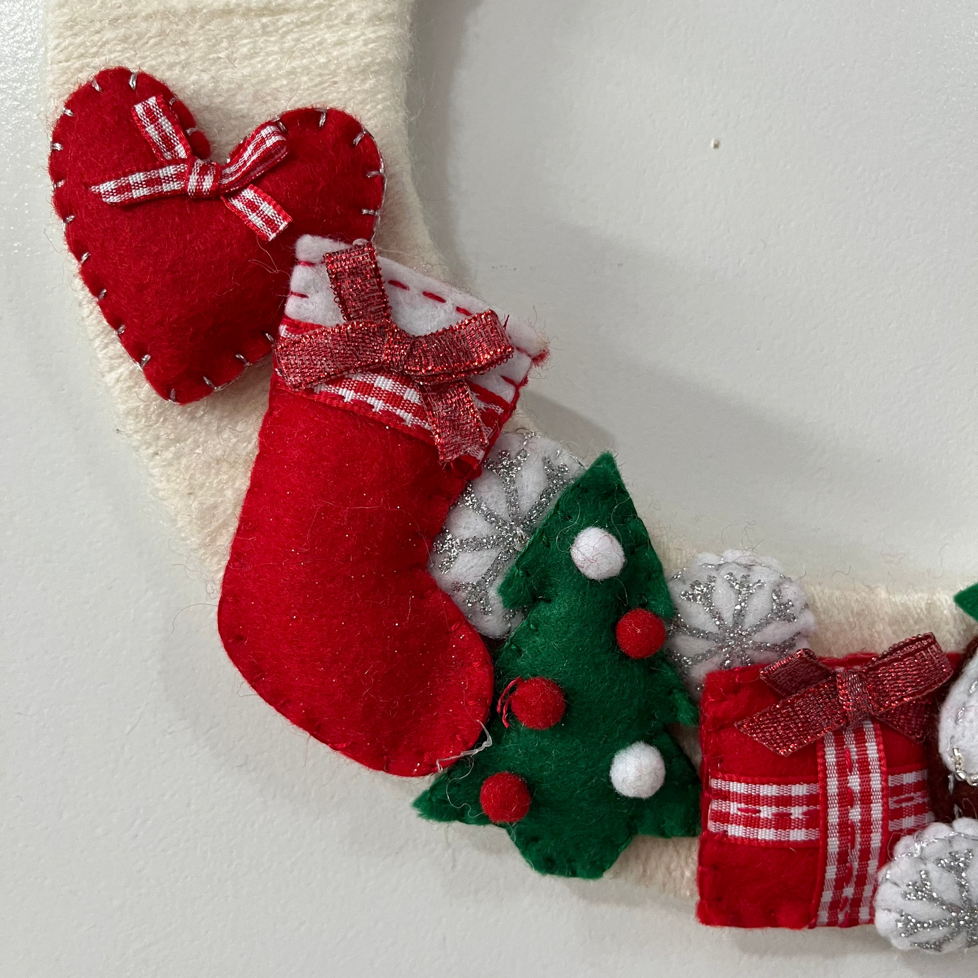 Close-up of a Christmas wreath featuring a red heart, stocking, tree, and present.