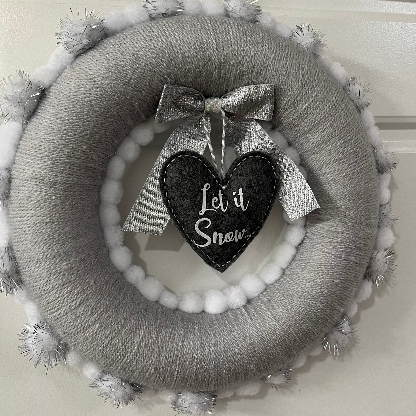 A festive gray and white wreath with a "Let it Snow" heart decoration in the center.