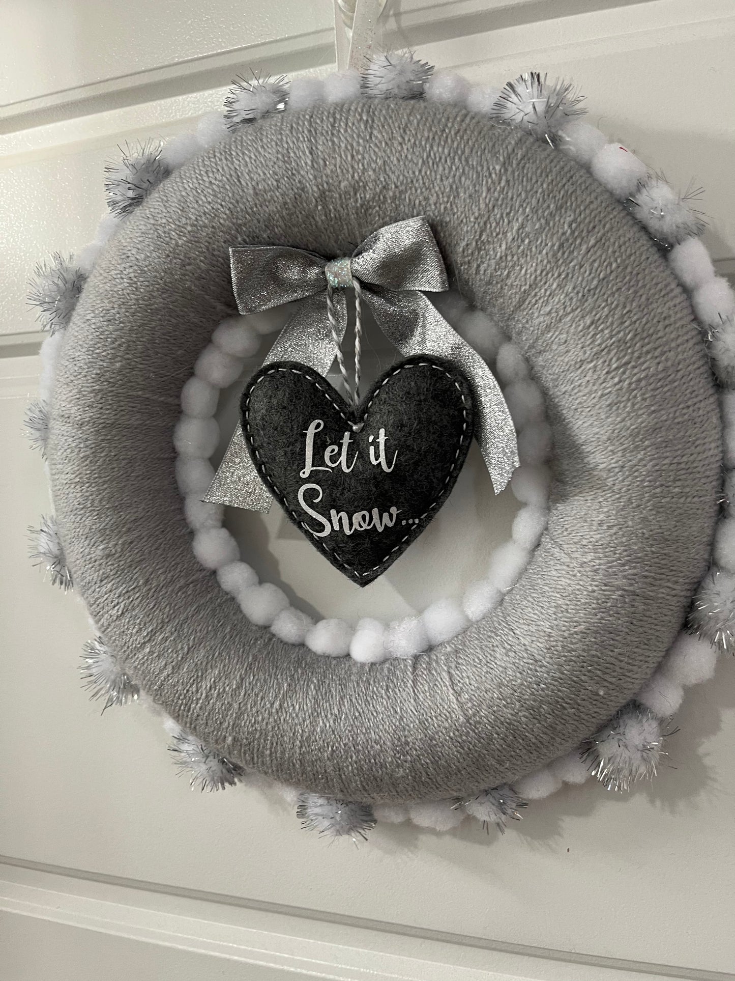Gray and white Christmas wreath with a “Let it Snow” heart hanging in the middle.