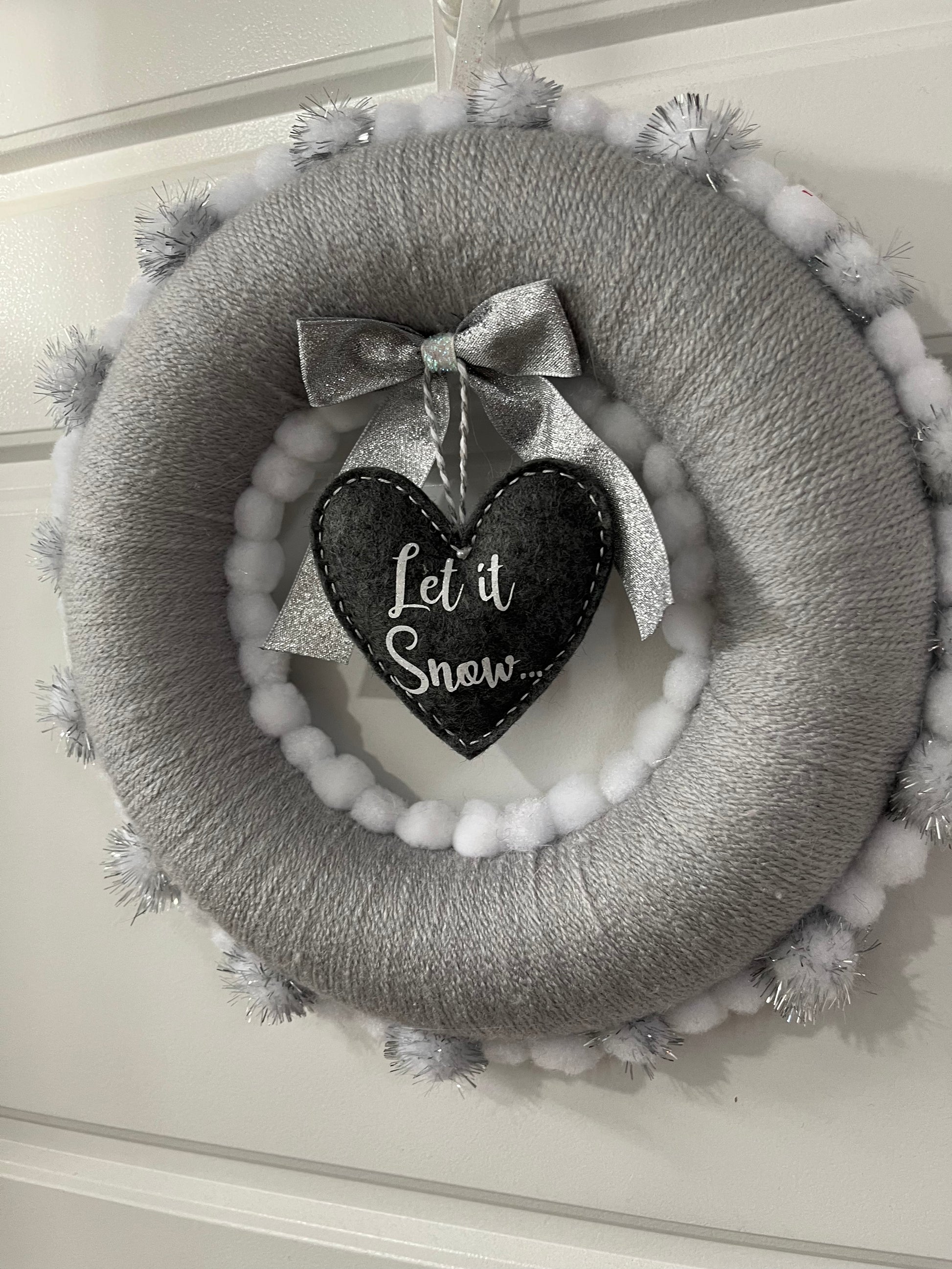Gray and white Christmas wreath with a “Let it Snow” heart hanging in the middle.