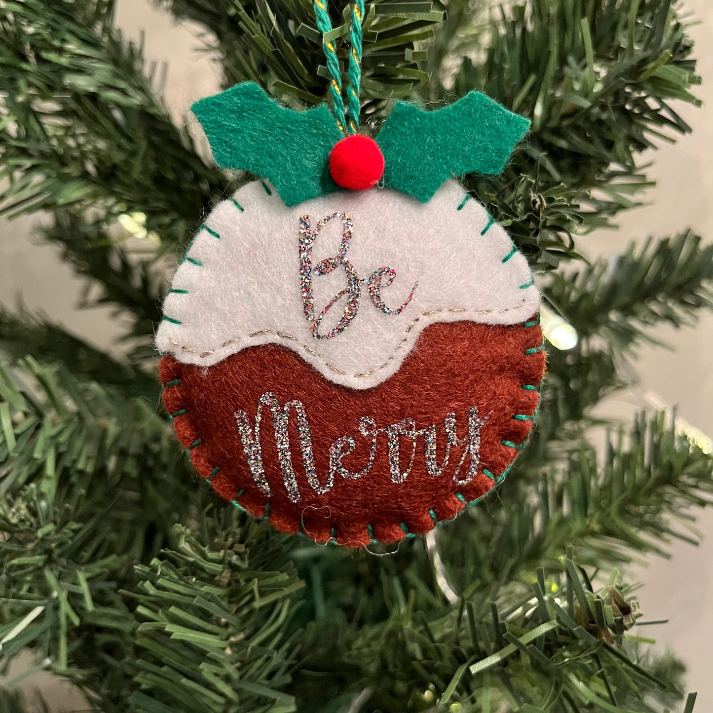 Handmade "Be Merry" Christmas pudding decoration on a Christmas tree.