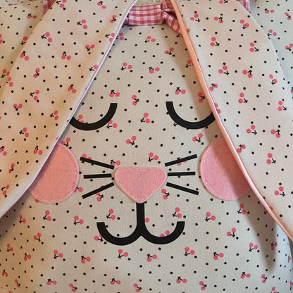Close-up of a fabric bunny face with pink cherry and black polka dot pattern, pink felt nose and cheeks.