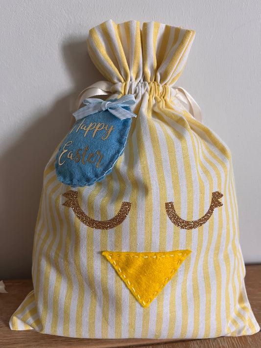 Yellow and white striped fabric bag with a chick face, glitter eyes, and a Happy Easter tag.