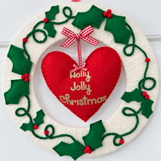 Festive Holly Jolly Christmas wreath with a red heart and green holly leaves.