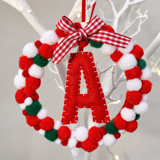 Red, white, and green pom-pom wreath with a red felt letter A and a gingham bow.