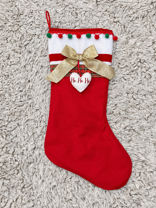 Red Christmas stocking with white cuff, gold bow, and "Ho Ho Ho" heart.