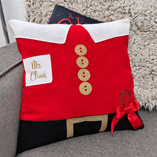 Red and black cushion designed as Santa's suit with gold buttons and a red bow.