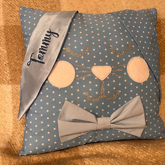Blue polka dot pillow with a bunny face, bow tie, and a ribbon with the name Tommy.