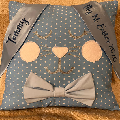 Blue polka dot pillow shaped like a bunny with a bow tie and personalized ribbons.