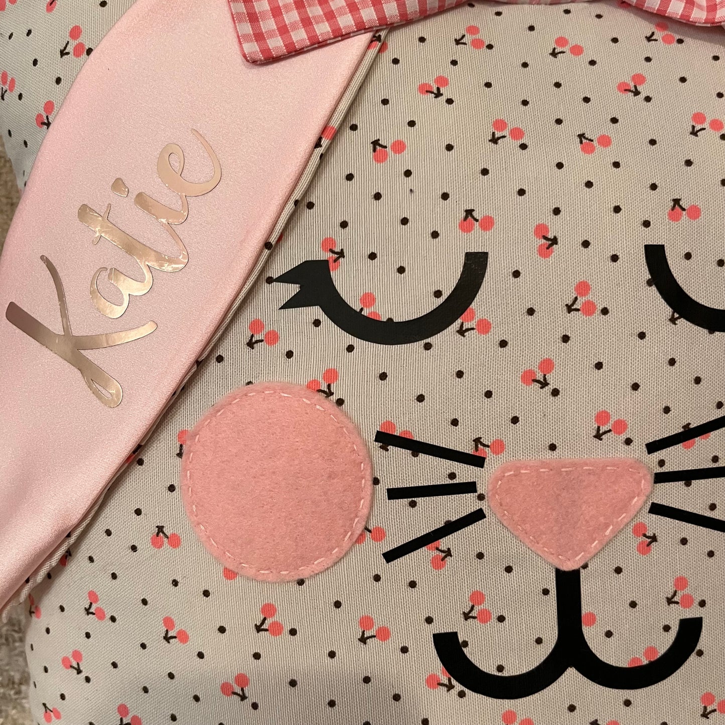 Close-up of a bunny pillow with the name Katie on its ear. It has a cherry pattern.